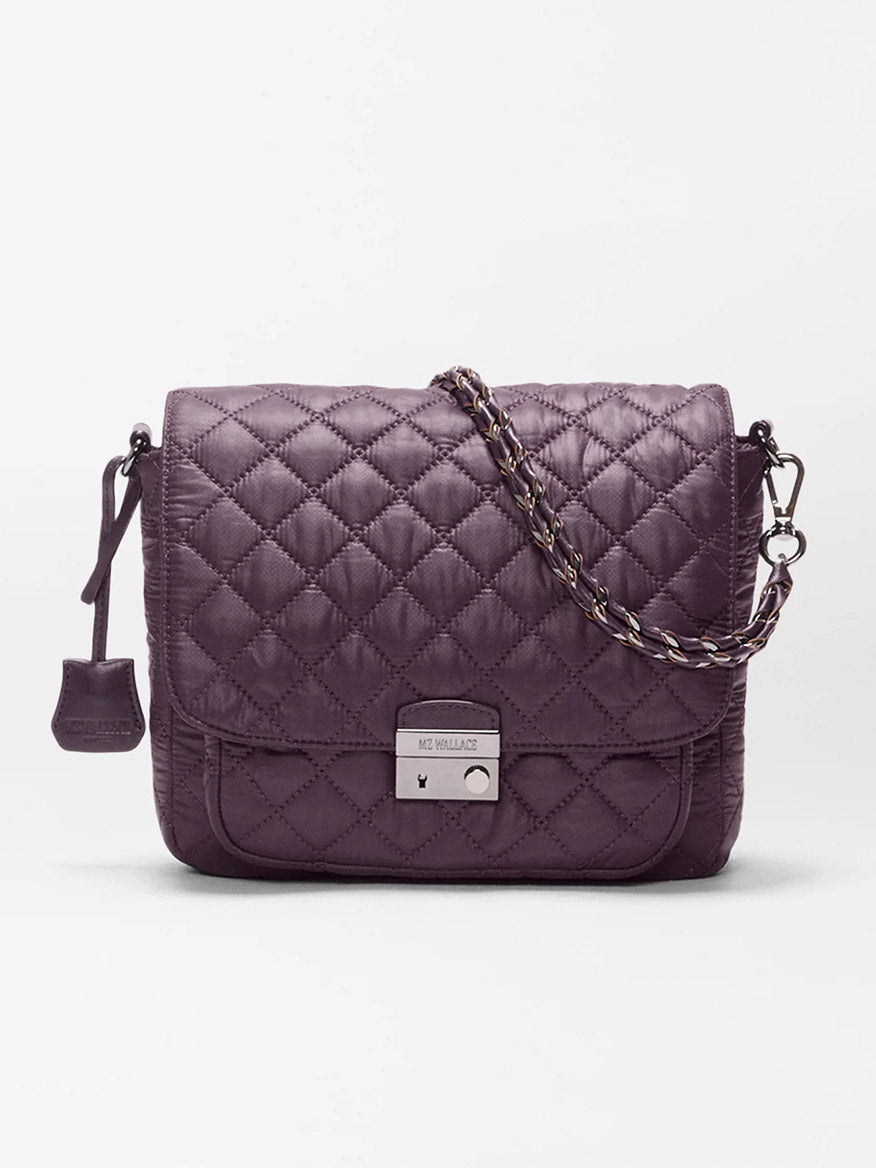The MZ Wallace Crosby Lock Medium Crossbody in Raisin Oxford is shown against a plain white background, featuring quilted purple fabric with Italian leather trim, a chain strap, and a silver clasp.