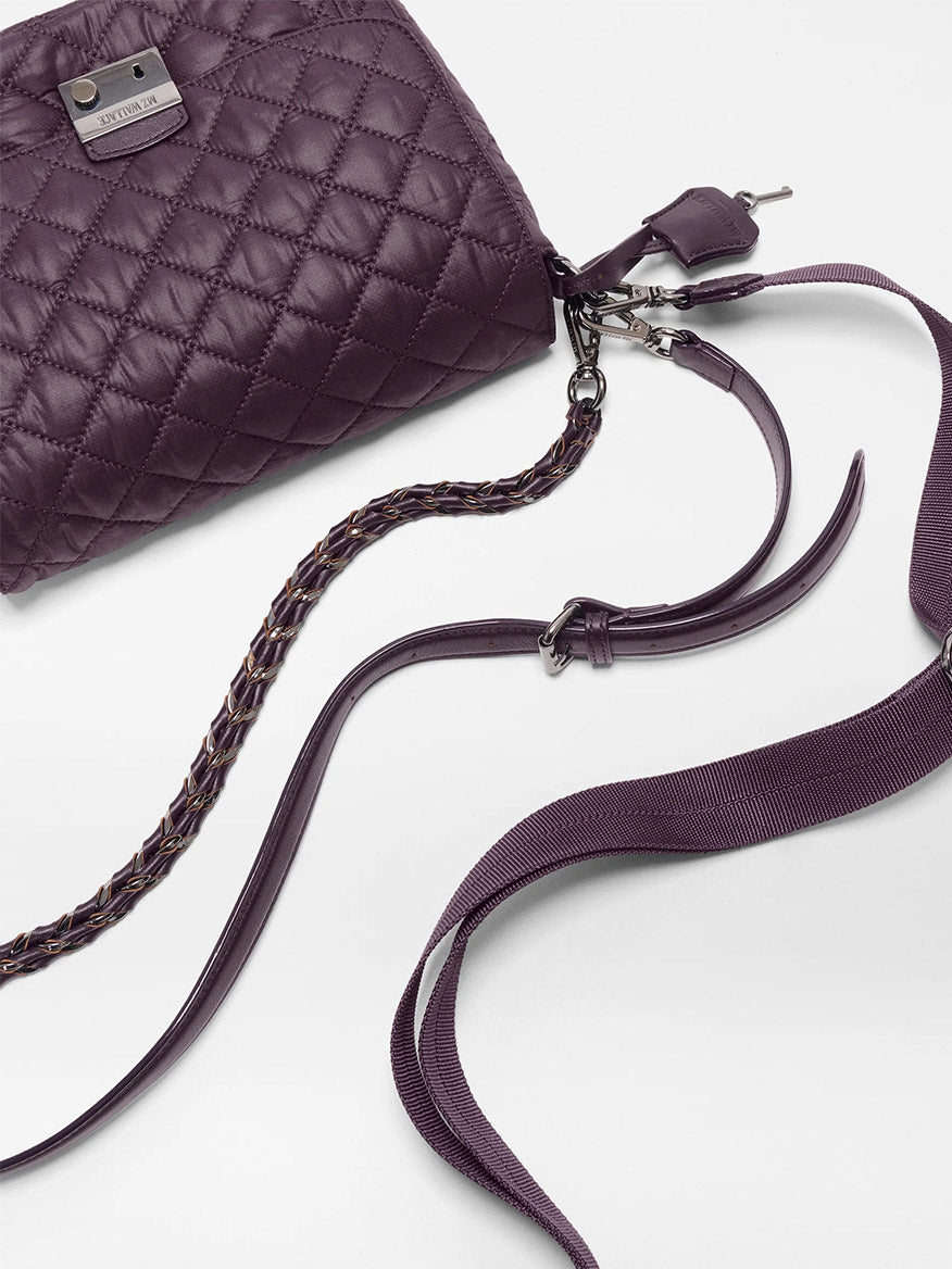 The MZ Wallace Crosby Lock Medium Crossbody in Raisin Oxford is a quilted purple recycled nylon handbag with Italian leather trim, featuring a metal logo plate, braided strap detail, and a detachable shoulder strap, displayed on a white surface.