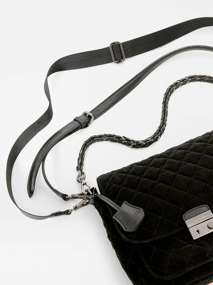 MZ Wallace Crosby Lock Medium Crossbody in black quilted velvet with a metal lock closure, braided chain strap, and adjustable webbing shoulder strap.