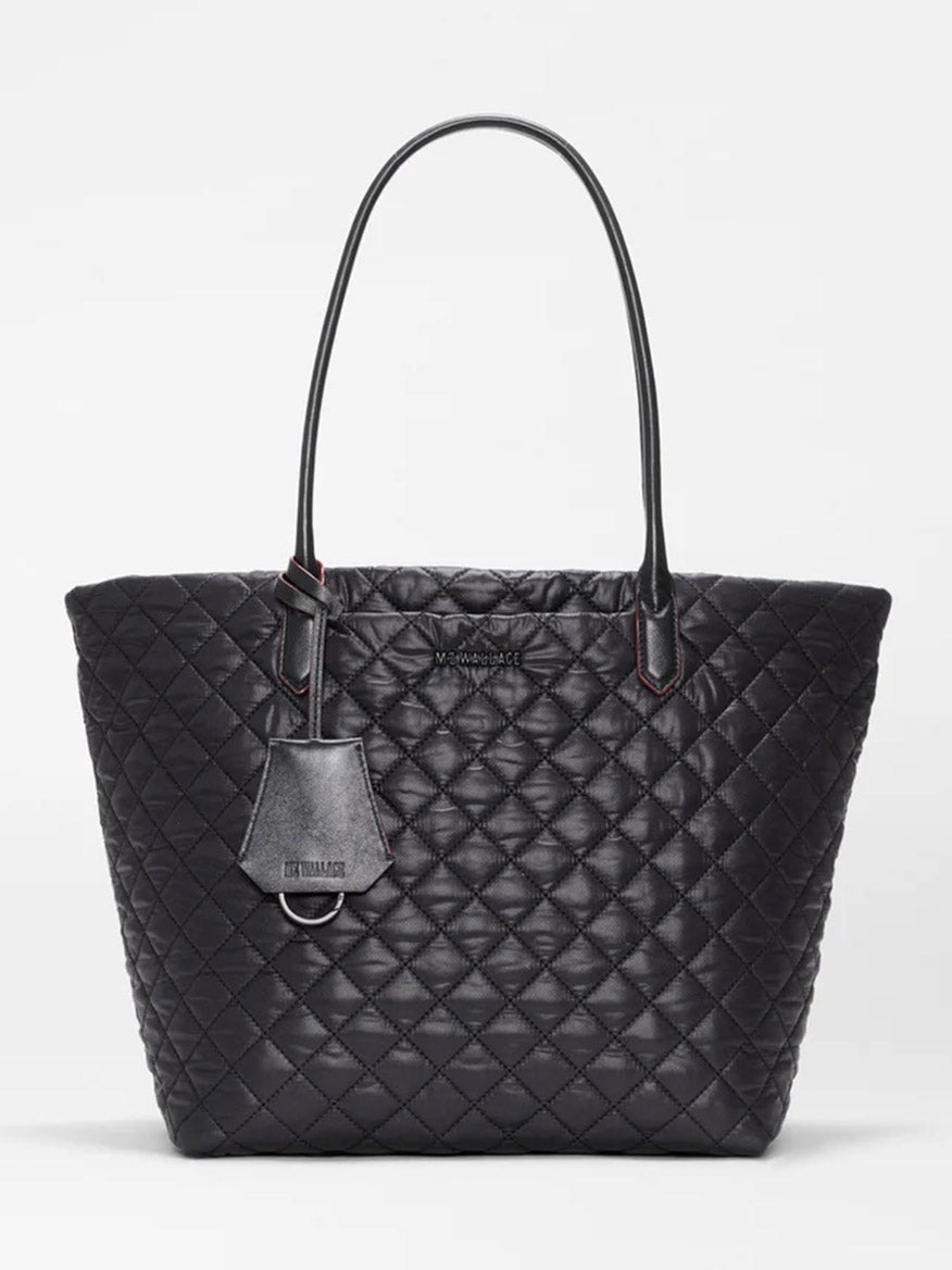 The MZ Wallace Medium Daily Tote in Black Oxford features a quilted leather design with two handles and a small tag, displayed against a plain white background. This stylish laptop tote blends elegance and practicality, making it perfect for everyday use.