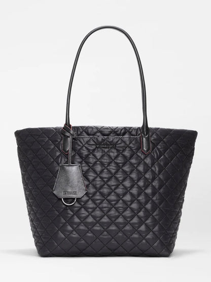 The MZ Wallace Medium Daily Tote in Black Oxford features a quilted leather design with two handles and a small tag, displayed against a plain white background. This stylish laptop tote blends elegance and practicality, making it perfect for everyday use.