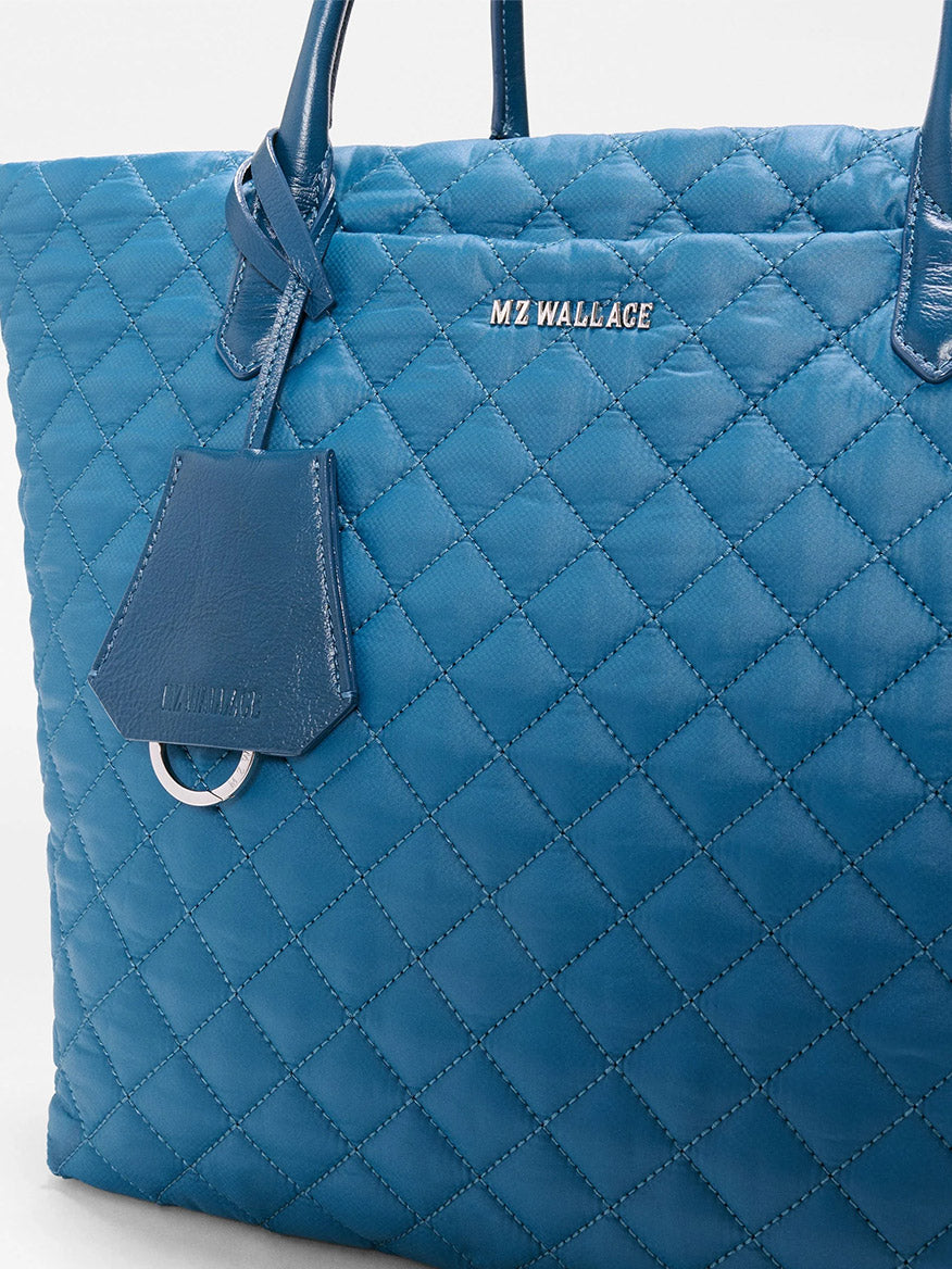 Close-up of the MZ Wallace Medium Daily Tote in Atlantic Blue Oxford, featuring double handles and a matching tag, crafted from recycled nylon—perfect as a stylish everyday laptop tote.