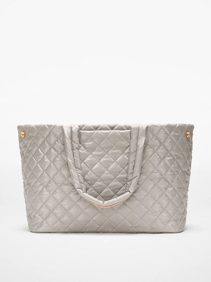The MZ Wallace Medium East West Metro Tote in Sable Pearl Metallic Oxford features a silver quilted design, double handles, gold-tone button accents, Italian leather trim, and a rectangular front pocket against a white background.
