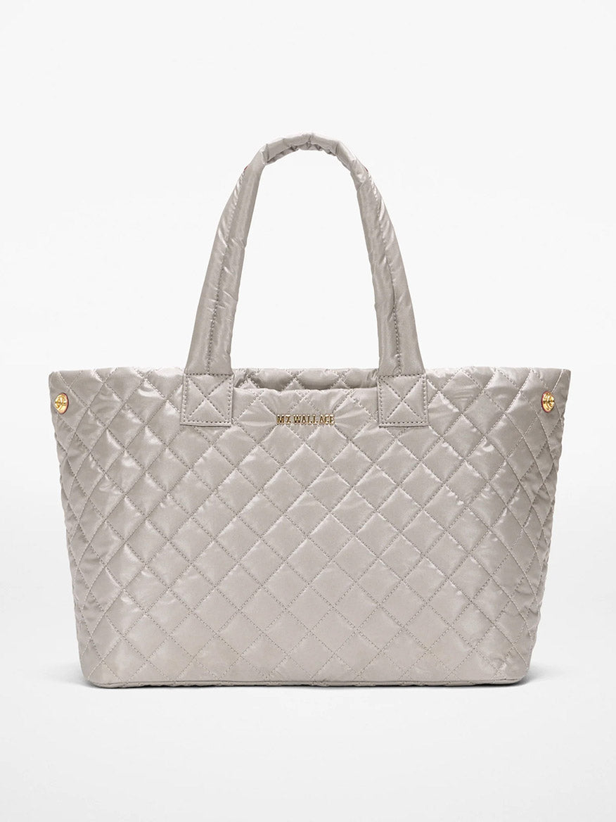 The MZ Wallace Medium East West Metro Tote in Sable Pearl Metallic Oxford features quilted silver-gray fabric, Italian leather trim, dual handles, gold-tone hardware, and a subtle front logo—stylish and ideal as a laptop bag.