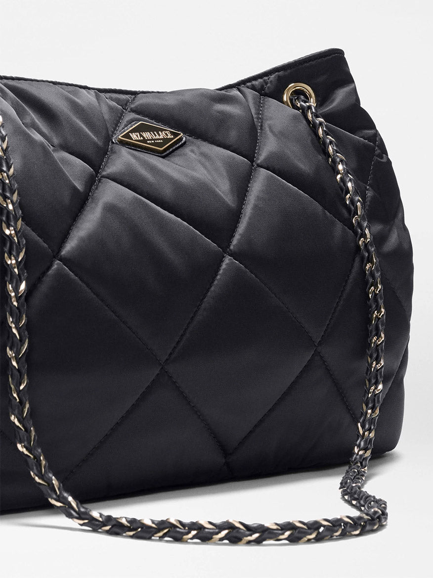 Close-up of the MZ Wallace Medium Frankie Tote in Black Bedford, showcasing its black quilted nylon finish, gold and black chain strap, adjustable crossbody strap, and a small metal logo plate on the front.