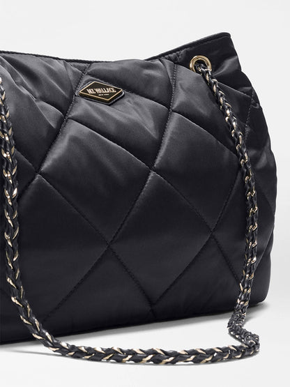 Close-up of the MZ Wallace Medium Frankie Tote in Black Bedford, showcasing its black quilted nylon finish, gold and black chain strap, adjustable crossbody strap, and a small metal logo plate on the front.