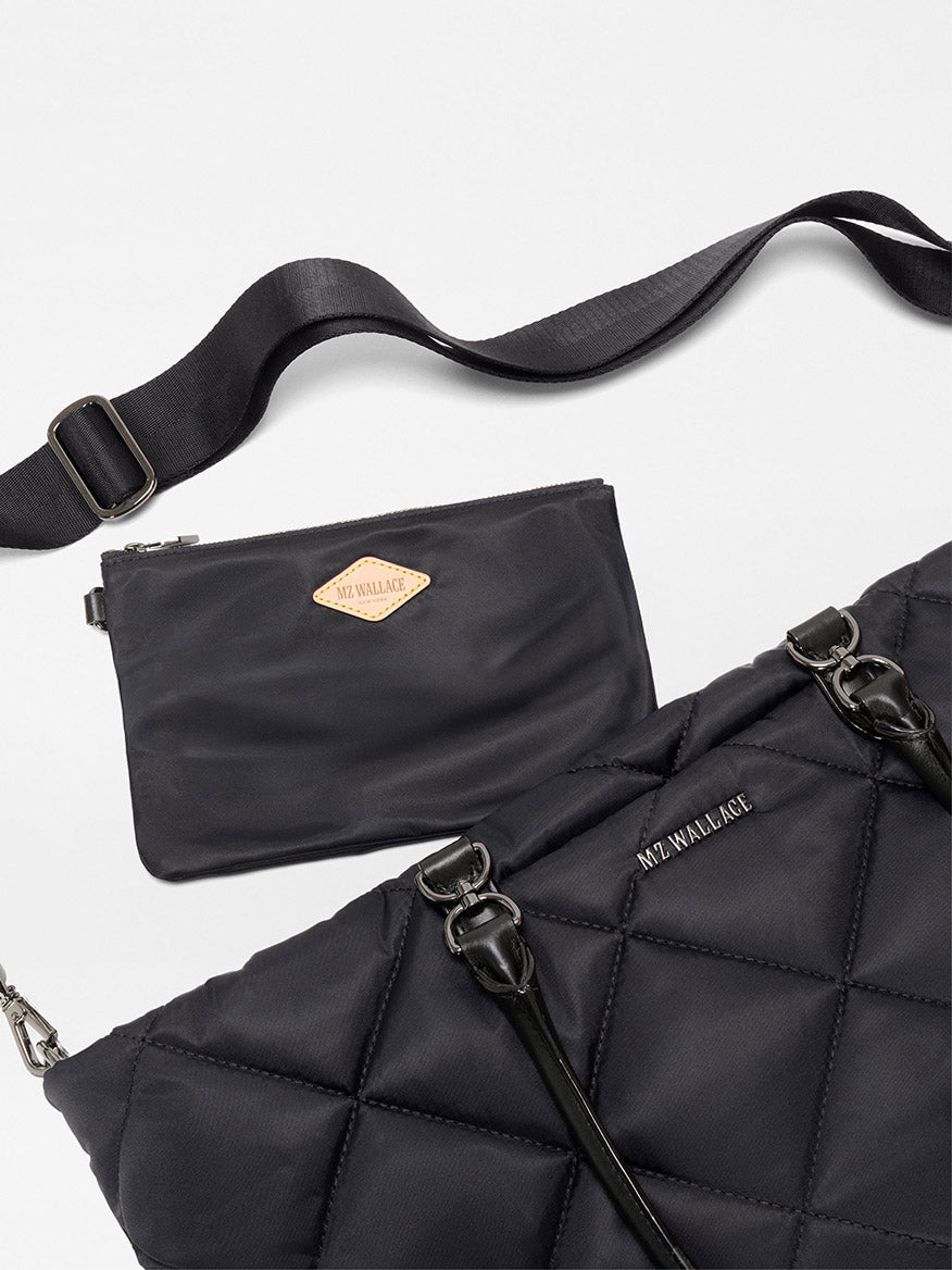 The MZ Wallace Medium Madison E-W Tote in Black Bedford features a black quilted design, Italian leather trim, metal hardware, a detachable adjustable nylon crossbody strap, and a matching black pouch—both with "MZ WALLACE" branding.
