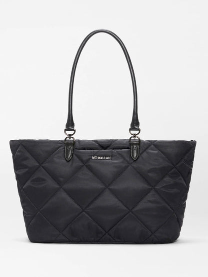 The MZ Wallace Medium Madison E-W Tote in Black Bedford features a black quilted slim east-west silhouette, double handles, Italian leather trim, and a small front logo, shown against a plain white background.