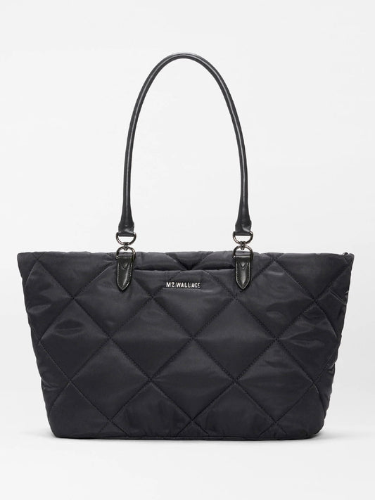 The MZ Wallace Medium Madison E-W Tote in Black Bedford features a black quilted slim east-west silhouette, double handles, Italian leather trim, and a small front logo, shown against a plain white background.