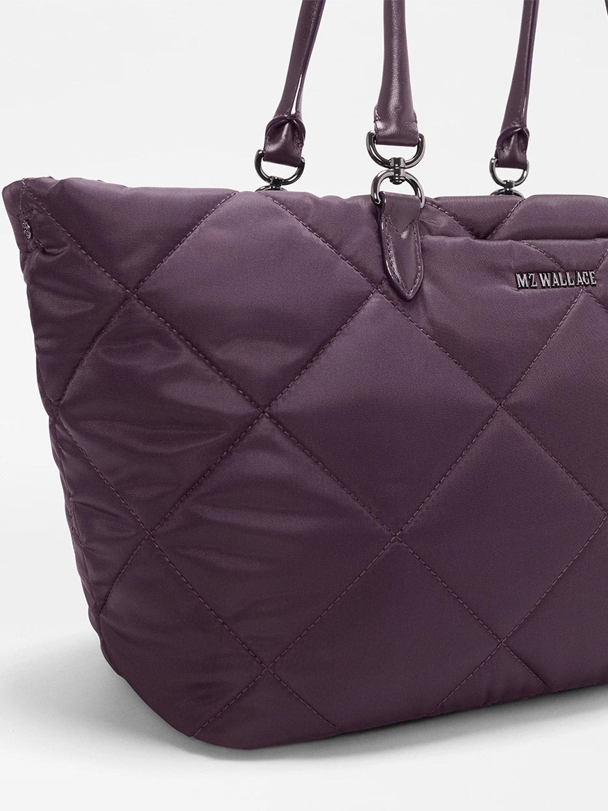 Close-up of the MZ Wallace Medium Madison E-W Tote in Raisin Oxford, featuring quilted nylon in a rich plum shade, double handles, and a small “MZ WALLACE” logo on the front.