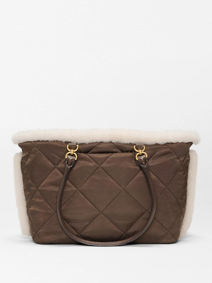 The MZ Wallace Medium Madison E-W Tote in Shearling & Walnut features brown quilted nylon, cream shearling trim, and dark brown double handles, shown against a plain white background.