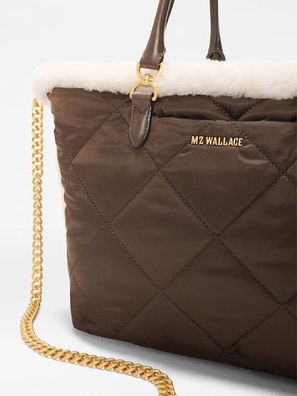 Close-up of the MZ Wallace Medium Madison E-W Tote in Shearling & Walnut, featuring brown quilted nylon, white shearling trim, gold chain strap and logo, and leather handles.
