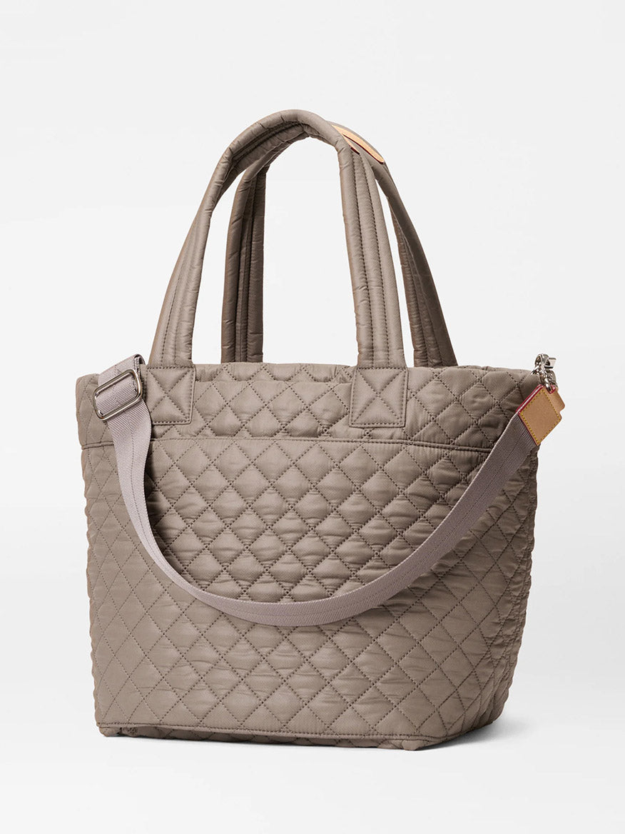 The MZ Wallace Medium Metro Tote Deluxe in Morning Dove Oxford features two short handles, a detachable adjustable crossbody strap, and a luggage sleeve, shown on a plain white background.