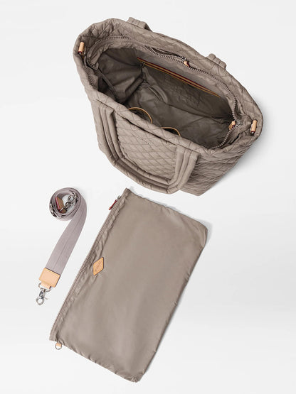 The MZ Wallace Medium Metro Tote Deluxe in Morning Dove Oxford is shown open with a zippered pouch and an adjustable crossbody strap beside it, highlighting its luggage sleeve tote design on a white background.