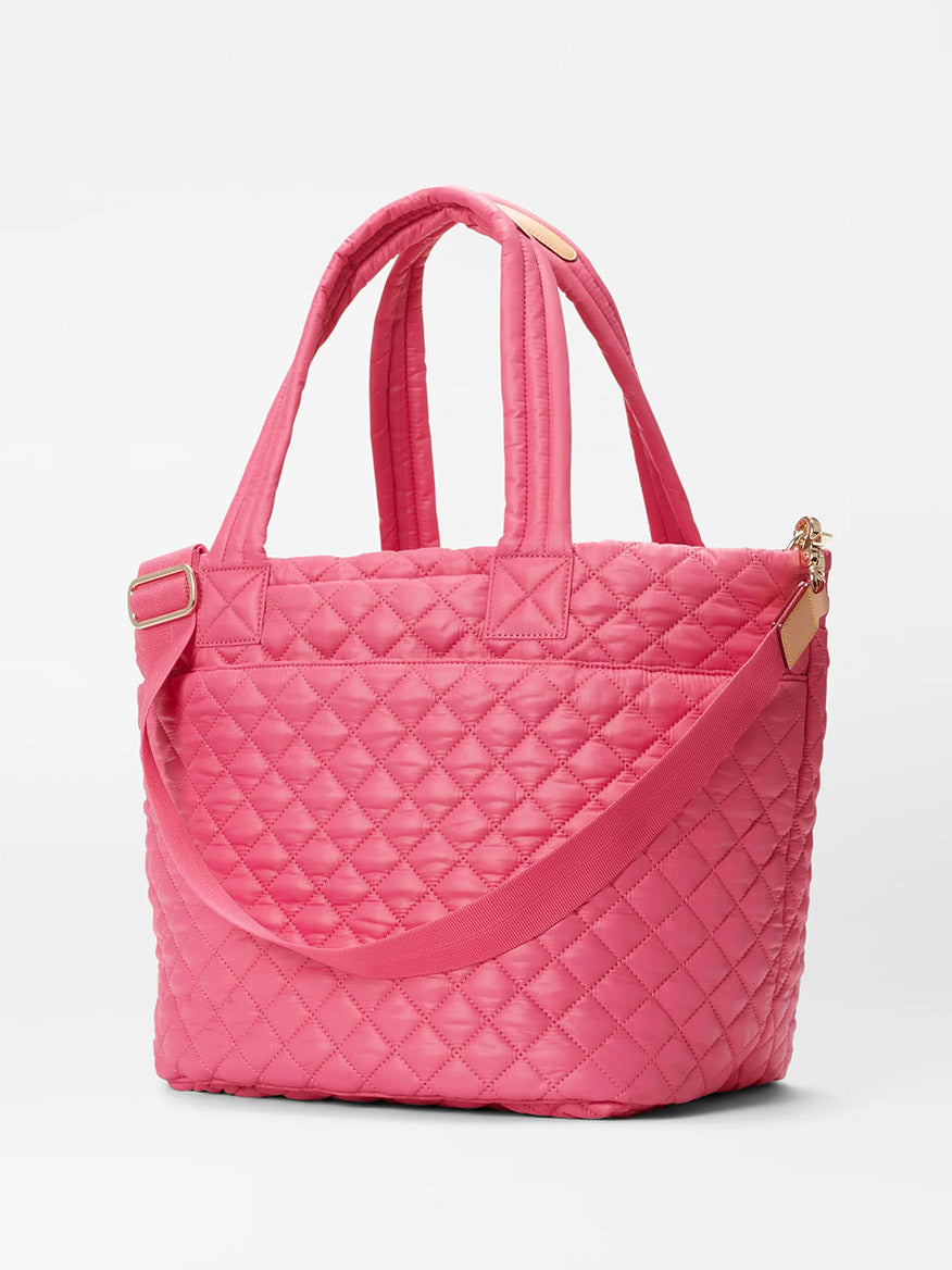 A pink quilted MZ Wallace Medium Metro Tote Deluxe in Zinnia Oxford with matching straps and gold hardware, displayed against a white background.
