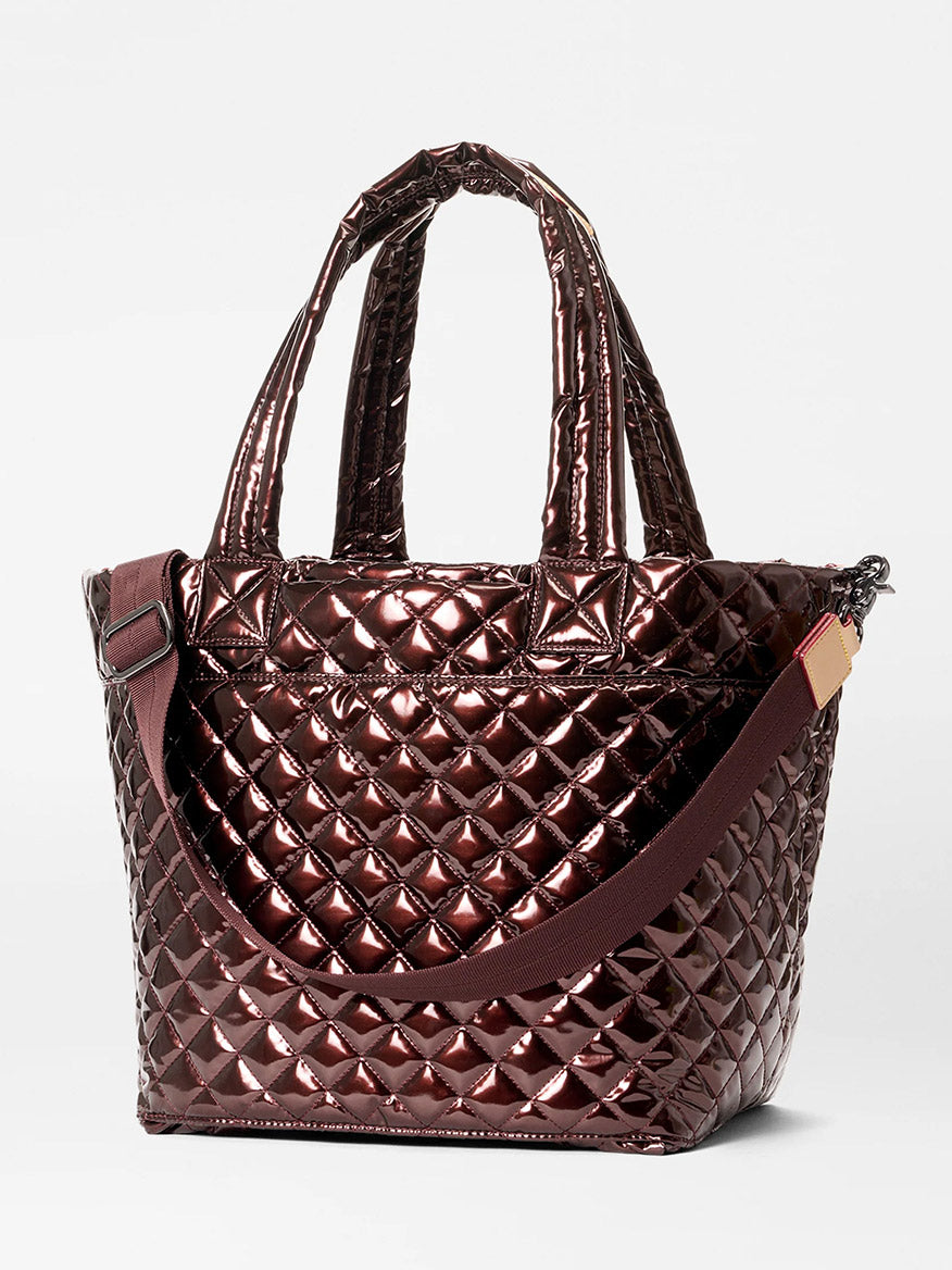 The MZ Wallace Medium Metro Tote Deluxe in Bordeaux Lacquer Oxford features a metallic quilted design, dual handles, and a detachable shoulder strap—ideal as a chic travel bag, showcased on a plain white background.