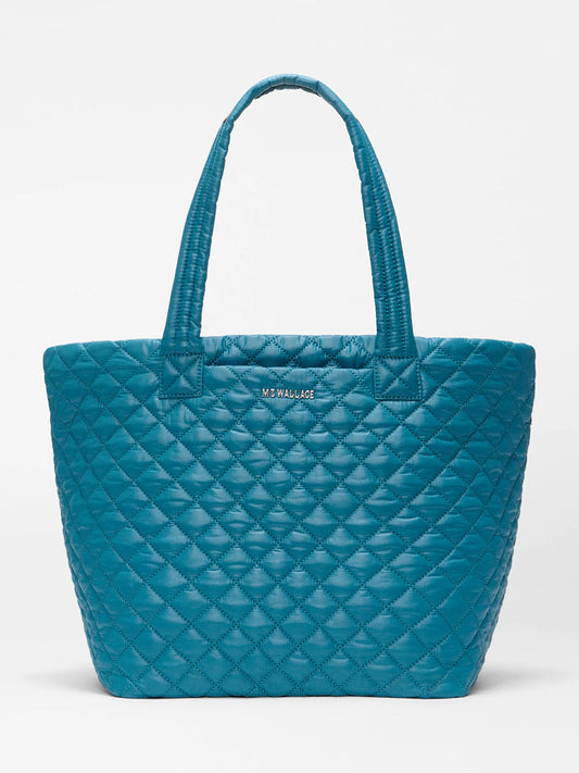The MZ Wallace Medium Metro Tote Deluxe in Pacific Oxford is a teal, featherlight quilted bag with double handles and a visible front logo, shown against a plain white background.