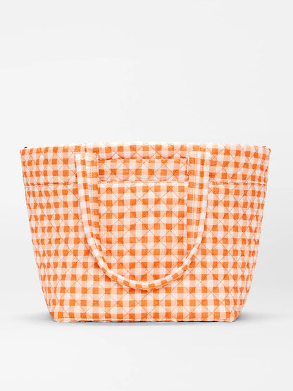 The MZ Wallace Medium Metro Tote Deluxe in Sunset Orange Gingham Oxford features quilted recycled nylon, two handles, and is ideal for work or travel. Shown against a plain white background.