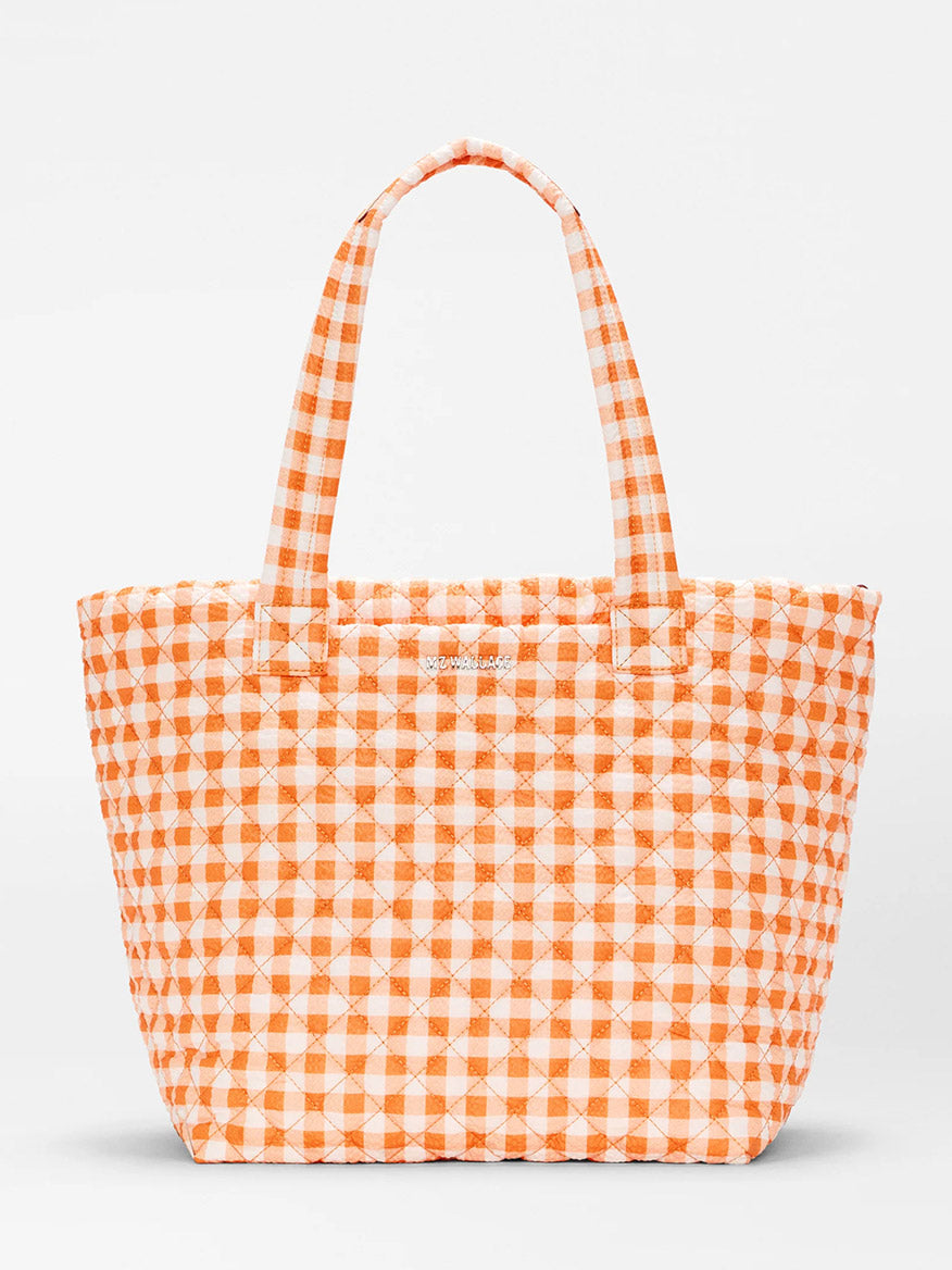 The MZ Wallace Medium Metro Tote Deluxe in Sunset Orange Gingham Oxford features quilted recycled nylon, an orange and white gingham check, and two handles—ideal for work or travel—shown against a plain white background.