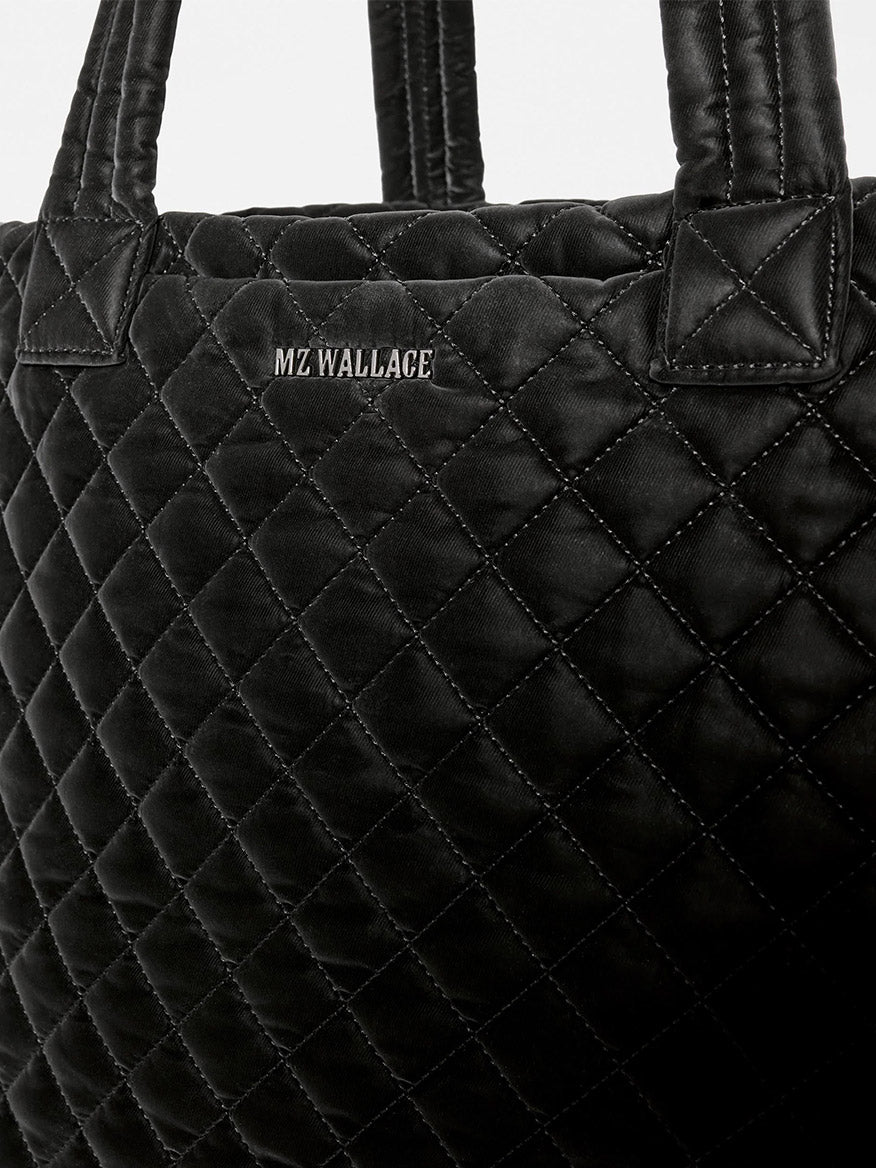 Black quilted MZ Wallace Medium Metro Tote Deluxe in Black Velvet Finish with two top handles and the brand name embroidered in silver thread.