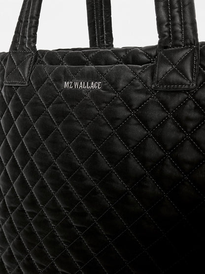 Black quilted MZ Wallace Medium Metro Tote Deluxe in Black Velvet Finish with two top handles and the brand name embroidered in silver thread.