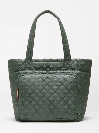 The MZ Wallace Medium Metro Travel Tote in Juniper Oxford is a green quilted recycled Oxford nylon bag featuring two handles and a front zippered pocket, displayed against a plain white background.