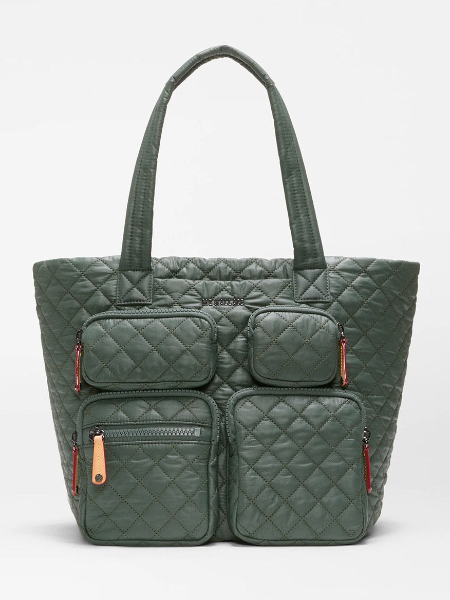 Introducing the MZ Wallace Medium Metro Travel Tote in Juniper Oxford, a dark green quilted travel bag crafted from recycled Oxford nylon. It features two long handles and four exterior zippered pockets on the front, combining eco-friendly materials with stylish design for your travels.