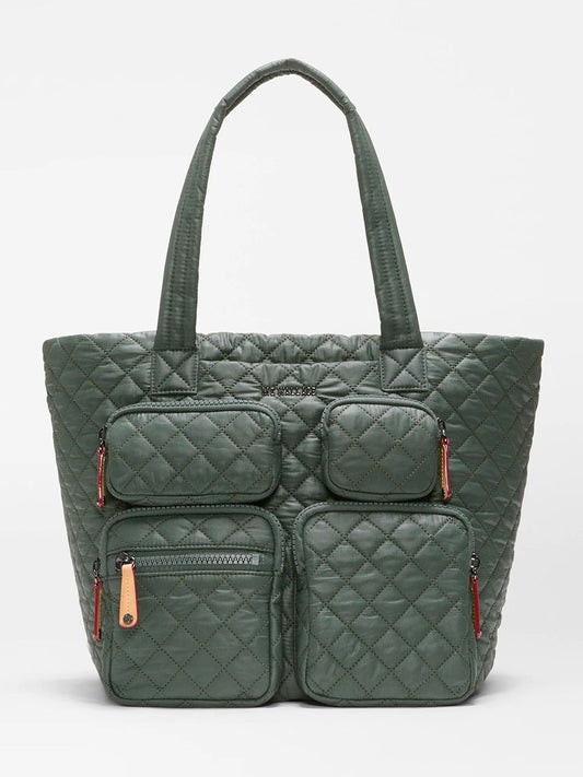 Introducing the MZ Wallace Medium Metro Travel Tote in Juniper Oxford, a dark green quilted travel bag crafted from recycled Oxford nylon. It features two long handles and four exterior zippered pockets on the front, combining eco-friendly materials with stylish design for your travels.