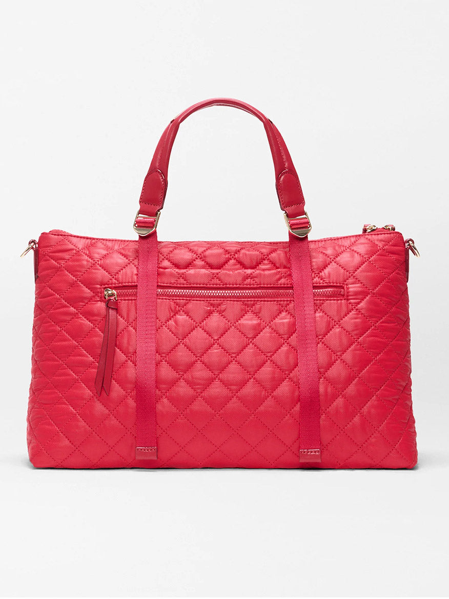 The MZ Wallace Medium Park Satchel in Apple Oxford features red quilted material, two top handles, a front zip pocket, and vertical strap details. This everyday bag is shown against a plain white background.
