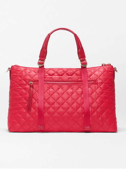 The MZ Wallace Medium Park Satchel in Apple Oxford features red quilted material, two top handles, a front zip pocket, and vertical strap details. This everyday bag is shown against a plain white background.