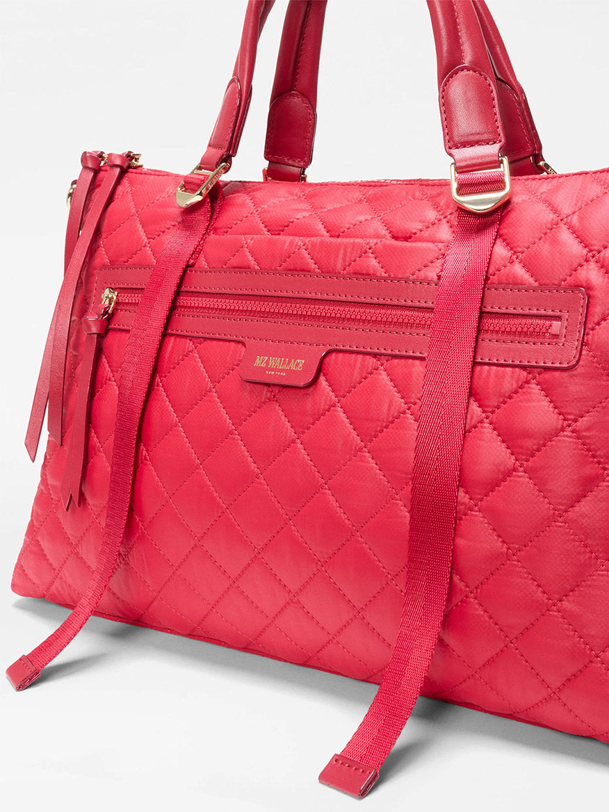 A close-up of the MZ Wallace Medium Park Satchel in Apple Oxford—this quilted red handbag with gold hardware, front zipper pocket, and dual shoulder straps is a stylish pick to elevate your everyday look.
