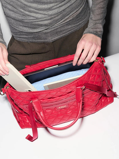 A person places a closed laptop and notebook into the open MZ Wallace Medium Park Satchel in Apple Oxford, showcasing its versatility as the perfect everyday bag.