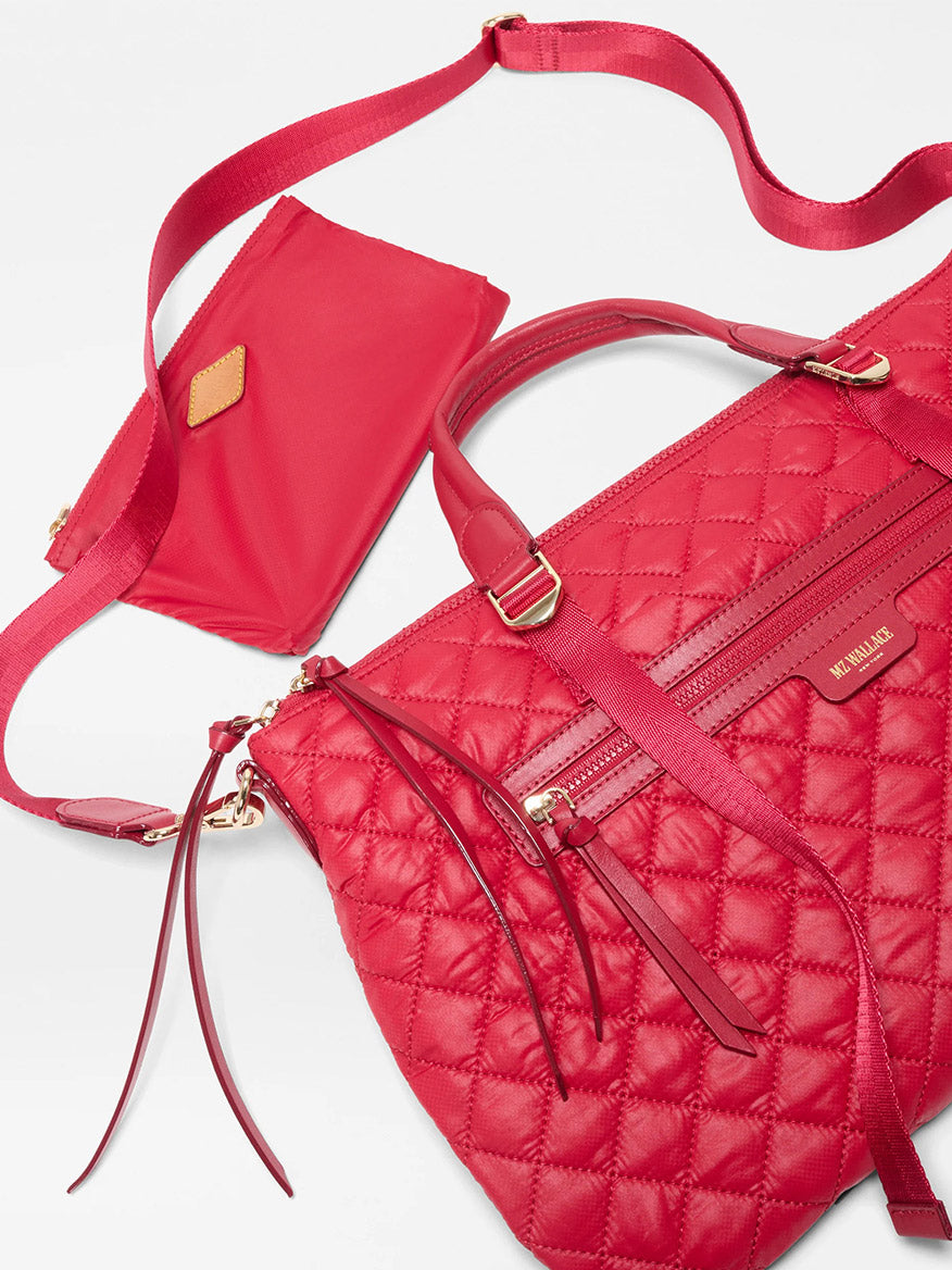 The MZ Wallace Medium Park Satchel in Apple Oxford features quilted red fabric, gold zippers and hardware, a matching shoulder strap, and a coordinating pouch—an elegant structured work bag ideal for everyday use.