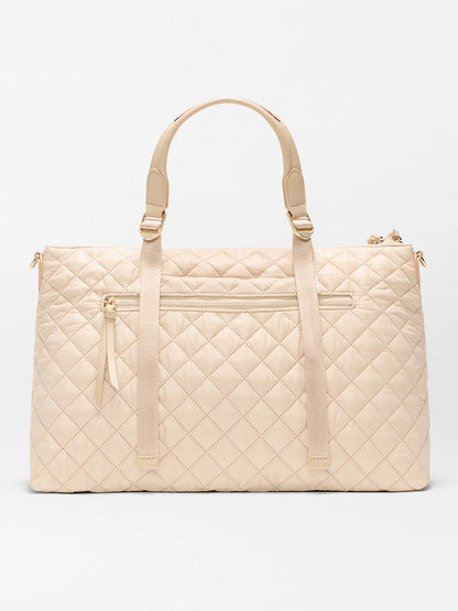 The MZ Wallace Medium Park Satchel in Buff Oxford features a beige quilted design, two top handles, a front zip pocket, and gold-tone hardware—ideal for everyday use—shown against a plain white background.