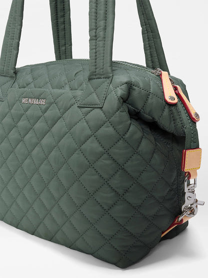 Introducing the MZ Wallace Medium Sutton Deluxe in Juniper Oxford—a green quilted handbag made from recycled Oxford nylon. It features double handles, a metal zipper, and the “MZ Wallace” name displayed on the front, seamlessly combining everyday versatility with style and sustainability.