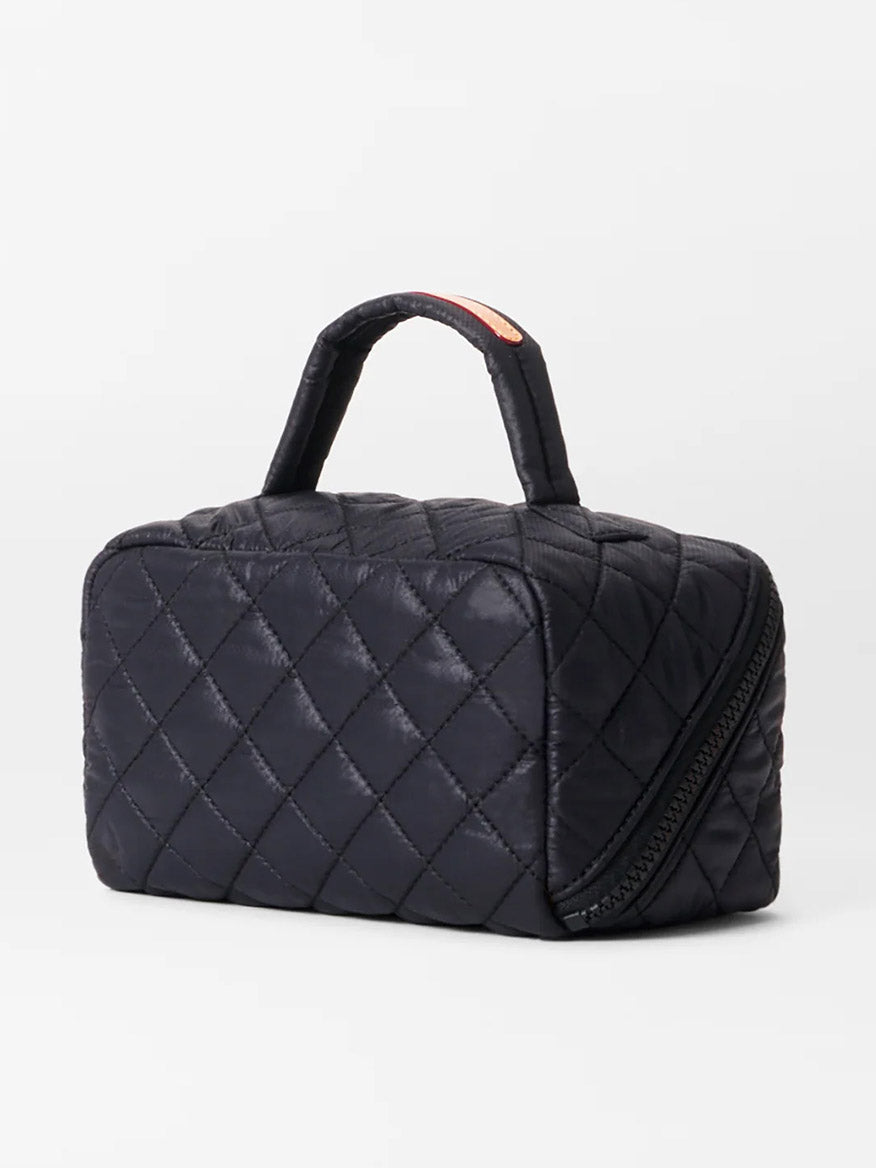 The MZ Wallace Metro Accordion Cosmetic II in Black Oxford is a black quilted rectangular bag with a top handle and angled zipper, made from durable Oxford fabric and accented with Italian leather trim, shown on a plain white background.
