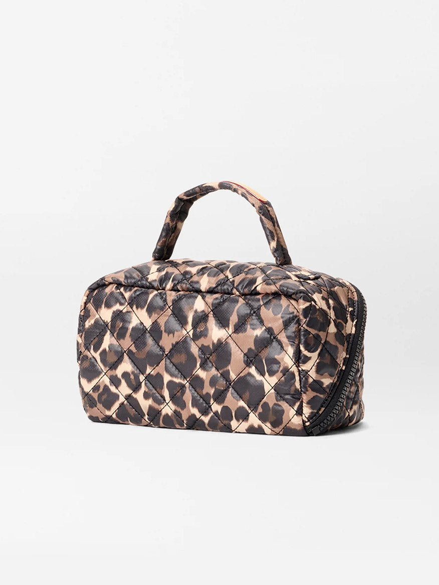 The MZ Wallace Metro Accordion Cosmetic II in Leopard Oxford is a small quilted bag with a handle, brown and black leopard print, interior pockets, and a zipper closure, shown against a plain white background.