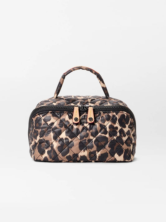 The MZ Wallace Metro Accordion Cosmetic II in Leopard Oxford is a small, rectangular quilted bag with a leopard print, oxford fabric, top handle, dual gold zipper pulls, and interior pockets, shown on a plain white background.