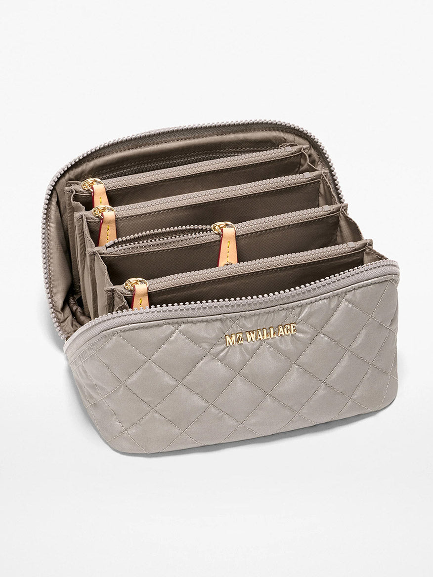 The MZ Wallace Metro Accordion Cosmetic II in Sable Pearl Metallic Oxford features quilted gray fabric, gold branding, and multiple interior compartments with tan pull tabs—perfect for organizing essentials in your laptop bag.