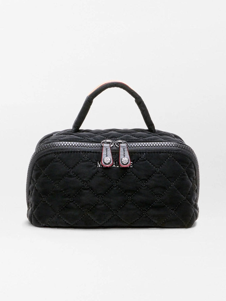 The MZ Wallace Metro Accordion Cosmetic II in Black Velvet Finish is a small black quilted fabric bag featuring a luxurious black velvet finish, silver zippers, Italian leather trim, and a short handle, shown against a plain white background.
