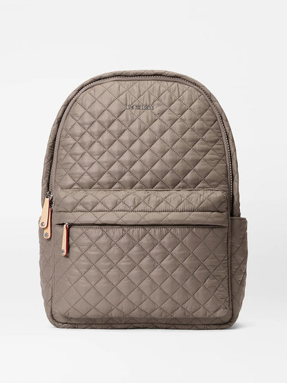 The MZ Wallace Metro Backpack II in Morning Dove Oxford, shown on a plain white background, features quilted taupe fabric, Italian leather trim, a front zip pocket, side pocket, top zipper closure, and a luggage sleeve.