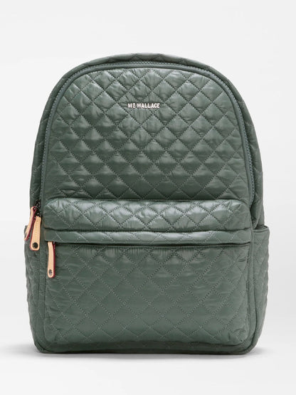Introducing the MZ Wallace Metro Backpack II in Juniper Oxford—a quilted dark green backpack featuring convenient front and side pockets, accented with tan zipper pulls. Made from durable recycled Oxford nylon, this stylish travel companion showcases the “MZ WALLACE” logo printed in white on the upper front.