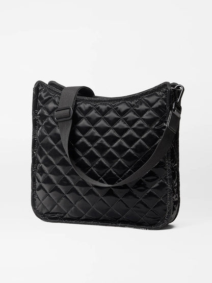 The MZ Wallace Metro Box Crossbody in Black Liquid Oxford, a black quilted shoulder bag crafted from liquid nylon fabric with an adjustable strap, is elegantly displayed against a plain background.