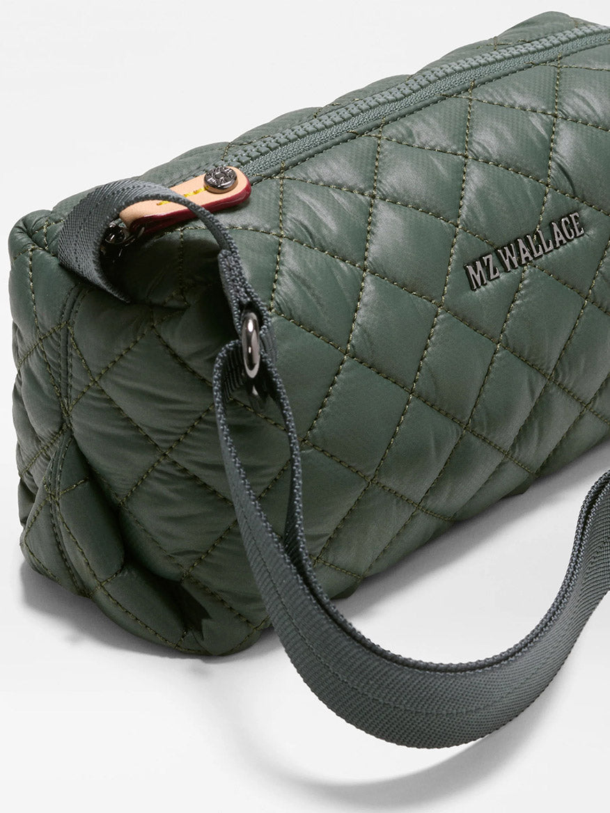 The MZ Wallace Metro East West Crossbody in Juniper is a compact, quilted green bag crafted from recycled nylon, featuring a black “MZ WALLACE” logo, dark gray strap, secure zipper closure, and diamond stitching—perfect for everyday use.