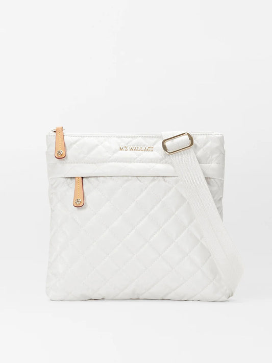 A quilted, MZ Wallace Metro Flat Crossbody in Pearl Metallic Oxford with an adjustable white strap and tan Italian leather accents, featuring a frontal zipper and branded tag.