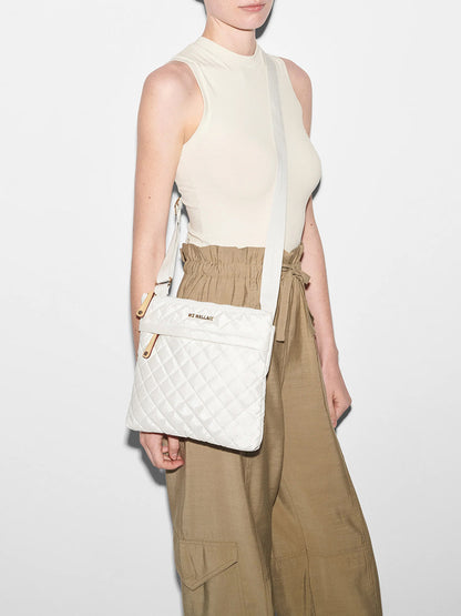 A woman in a sleeveless top and beige trousers wearing a MZ Wallace Metro Flat Crossbody in Pearl Metallic Oxford.