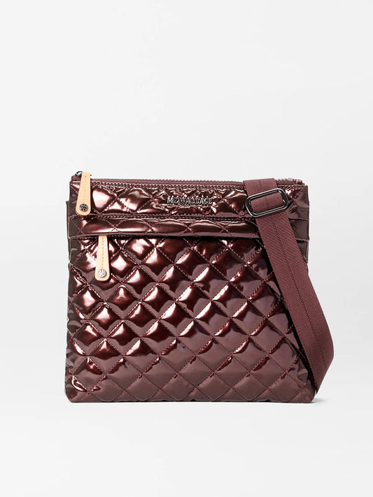 The MZ Wallace Metro Flat Crossbody in Bordeaux Lacquer Oxford features a quilted metallic burgundy finish, zippered top, front pocket, Italian leather trim, and an adjustable matching strap, shown against a plain white background.
