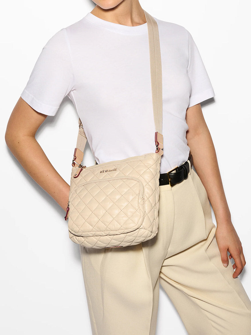 A person in a white t-shirt and beige pants is accessorizing with an MZ Wallace Metro Scout Deluxe in Buff Oxford.