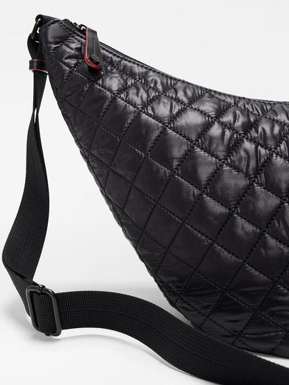 Close-up of the MZ Wallace Metro Smile Bag in Black Oxford, featuring quilted black nylon, Italian leather trim, an adjustable nylon strap, and a silver buckle against a plain background.