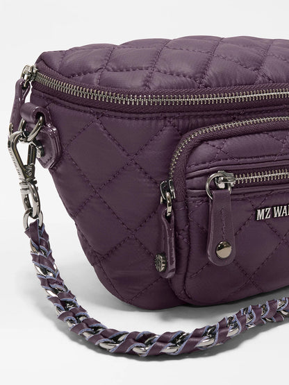 Close-up of the MZ Wallace Micro Crosby Crossbody Sling in Raisin Oxford—crafted from recycled nylon with a quilted finish, silver zippers, a small front pocket, and a chain-and-fabric shoulder strap for compact hands-free carrying.